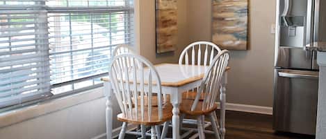 A dining area with a table and chairs, a refrigerator, and artwork on the walls.