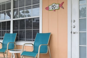 A building exterior with a number sign, a door, and two chairs.