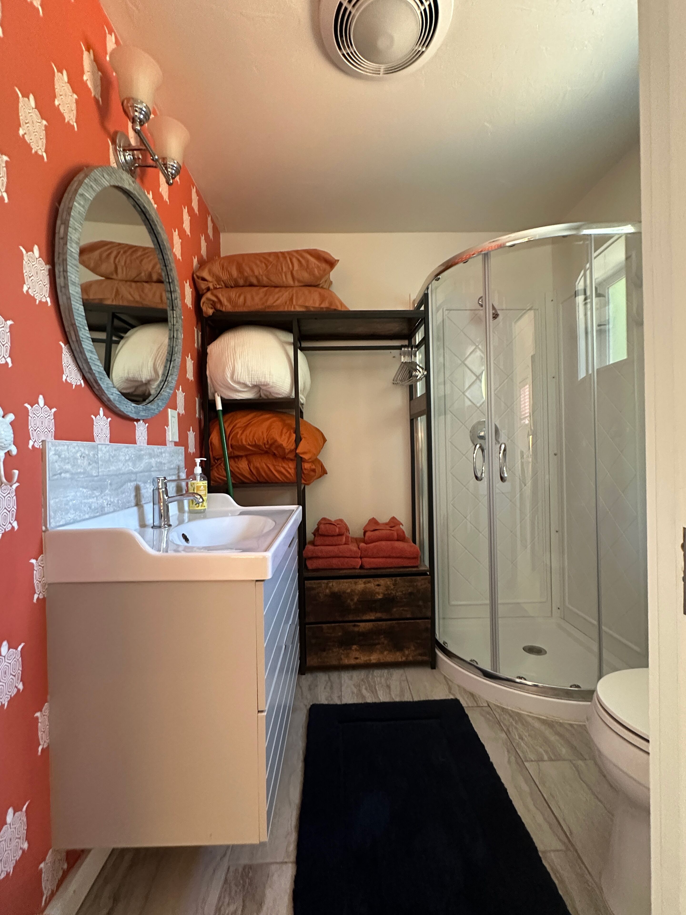 A compact bathroom with a sink, mirror, and shower.