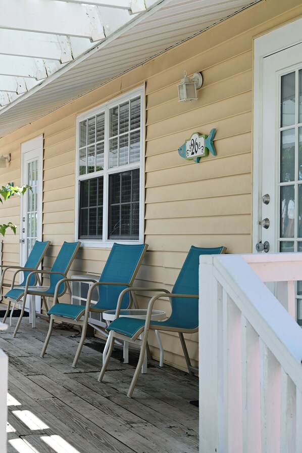 A porch with three chairs and a door.