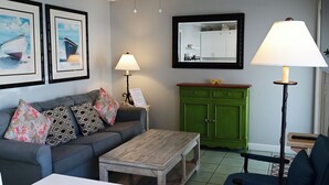 Un salon avec un canapé, une table basse, un meuble vert et une lampe.