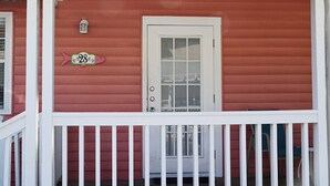 Une maison rouge avec une porte blanche et un panneau indiquant le numéro de la maison.