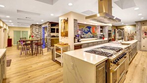 A modern kitchen with a central island, built-in appliances, and a dining area with bar stools. - Japanese Retreat (Las Vegas)