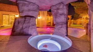 A pool area with a turtle sculpture, rock columns, and a building in the background. - Japanese Retreat (Las Vegas)