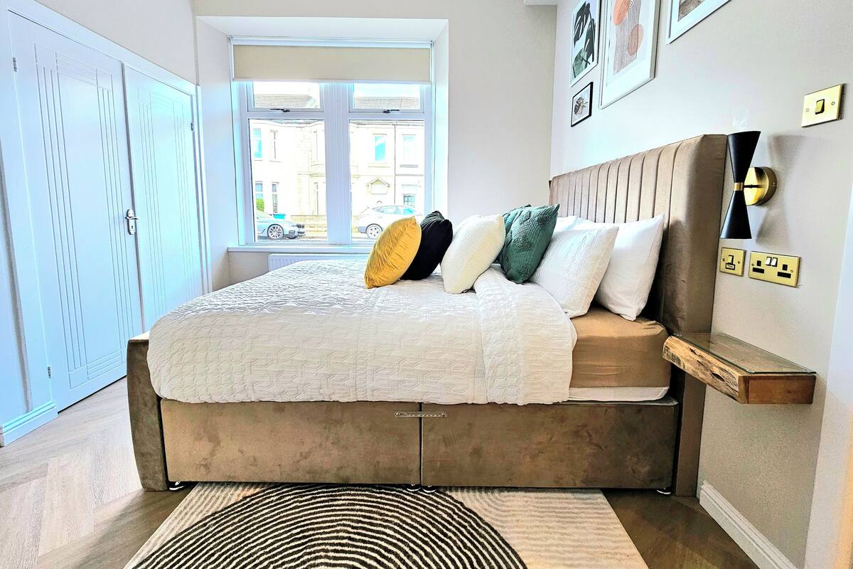 A bedroom with a bed, a window, a wardrobe, and a wall-mounted shelf.