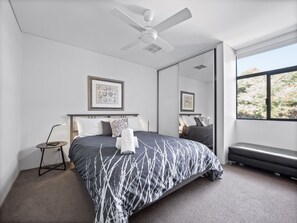 Relax in this serene bedroom with a large bed, ceiling fan, and comfortable seating area.