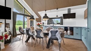 A modern kitchen with a dining area, featuring a large window, wooden ceiling, and a flat-screen TV. - 3 bedroom awesome home in Tarm (Tarm)