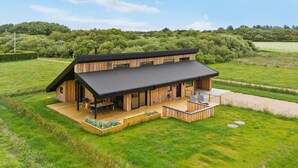 A modern wooden house with a large deck, surrounded by lush green fields and trees. - 3 bedroom awesome home in Tarm (Tarm)