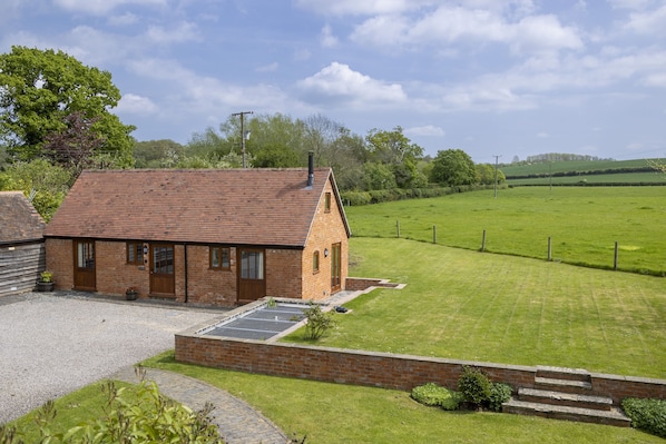 A brick house with a sloped roof, a gravel driveway, and a well-maintained lawn.