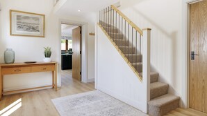 Ein modernes Interieur mit einem Holztisch, einer Treppe mit Holzhandlauf und einer Tür mit strukturierter Verkleidung.