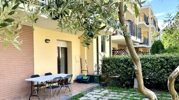 A courtyard with a table and chairs, a door, and a building with balconies. - SE097 - Senigallia, two-room apartment with garden (Senigallia)
