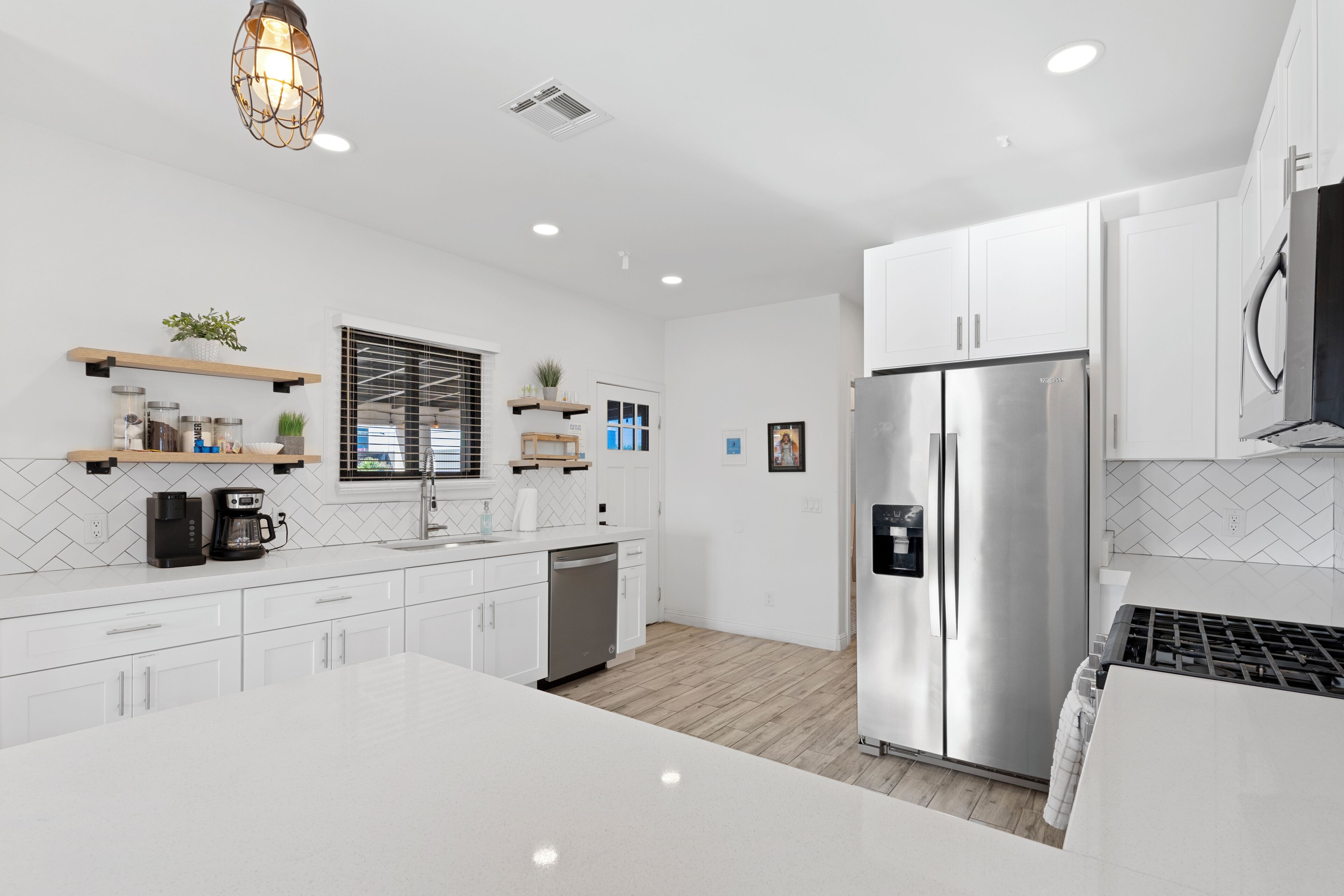 A modern kitchen with white cabinetry, a stainless steel refrigerator, and a central island.