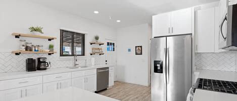 A modern kitchen with white cabinetry, a stainless steel refrigerator, and a central island.