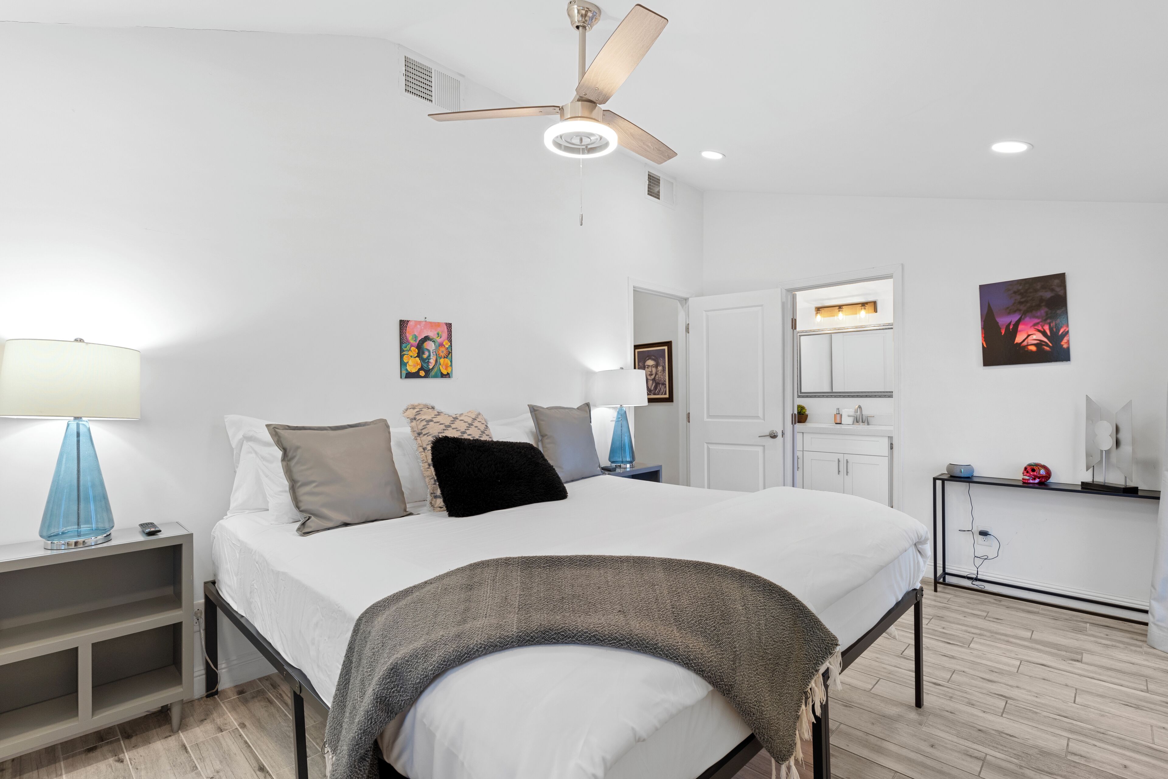 A modern bedroom with a bed, bedside tables, a ceiling fan, and a nightstand.