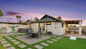 Un patio trasero con zona de estar, área de parrillada y una pérgola.