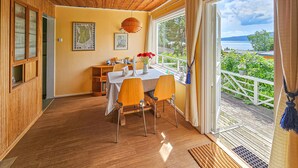 A dining area with a table and chairs, a map on the wall, and a view of greenery and water outside. - Nice home in Klokkarstua with WiFi (Klokkarstua)
