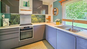 A compact kitchen with a built-in oven, a coffee maker, and a window with a view of greenery. - Nice home in Klokkarstua with WiFi (Klokkarstua)
