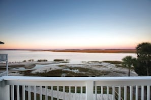 A coastal view from a balcony with a wooden deck, a sandy beach, and a calm sea. - Edisto Island | Beach Weekend w/ Friends | Pool + Beach | 3BR Sleeps 10 (Edisto Island)