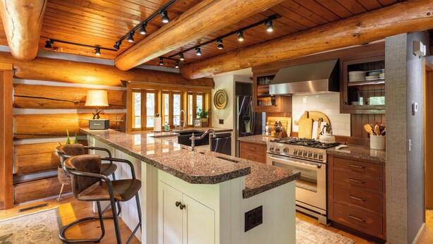 Een ruime keuken met houten balken, granieten aanrechtbladen en moderne apparatuur.