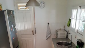 A kitchen with a refrigerator, sink, stove, and a clock on the wall. - Large T2 ground floor In the countryside of Fort de France (Fort-de-France)