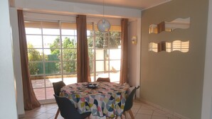 A dining area with a round table covered by a colorful tablecloth, surrounded by four chairs with wooden legs. - Large T2 ground floor In the countryside of Fort de France (Fort-de-France)
