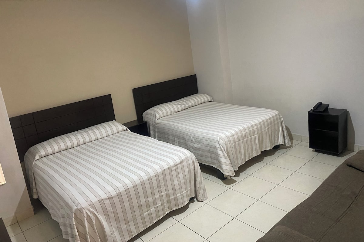 Ein Hotelzimmer mit zwei Betten, einem kleinen Schreibtisch und einem Telefon.