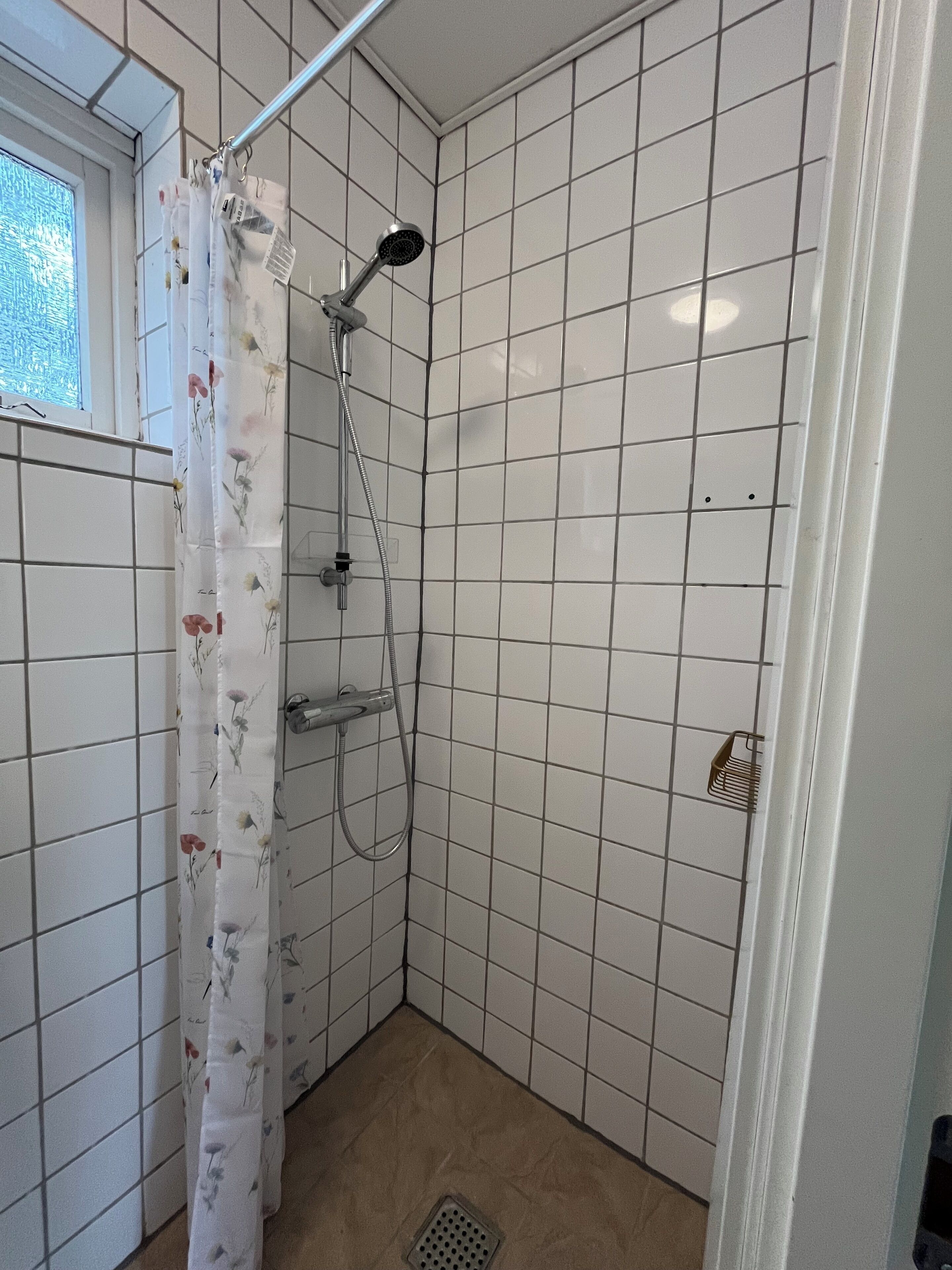 A small, tiled shower area with a showerhead and curtain.