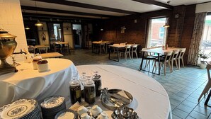 Zona pranzo con tavolo rotondo apparecchiato per un pasto, circondato da sedie.