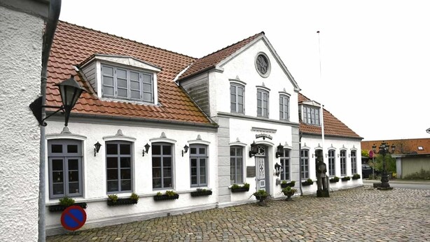 Un edificio bianco con tetto a tegole e numerose finestre, con un cartello che riporta la scritta "Brandenburg".
