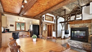 Un comedor amplio con una gran mesa y sillas de madera, una cocina con electrodomésticos modernos y una chimenea de piedra.