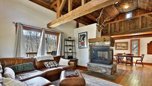 Una sala de estar acogedora con chimenea de piedra, sofás de cuero y vigas de madera.