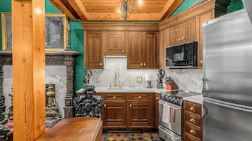 A kitchen with wooden cabinets, a marble countertop, a stainless steel refrigerator, and a stove.