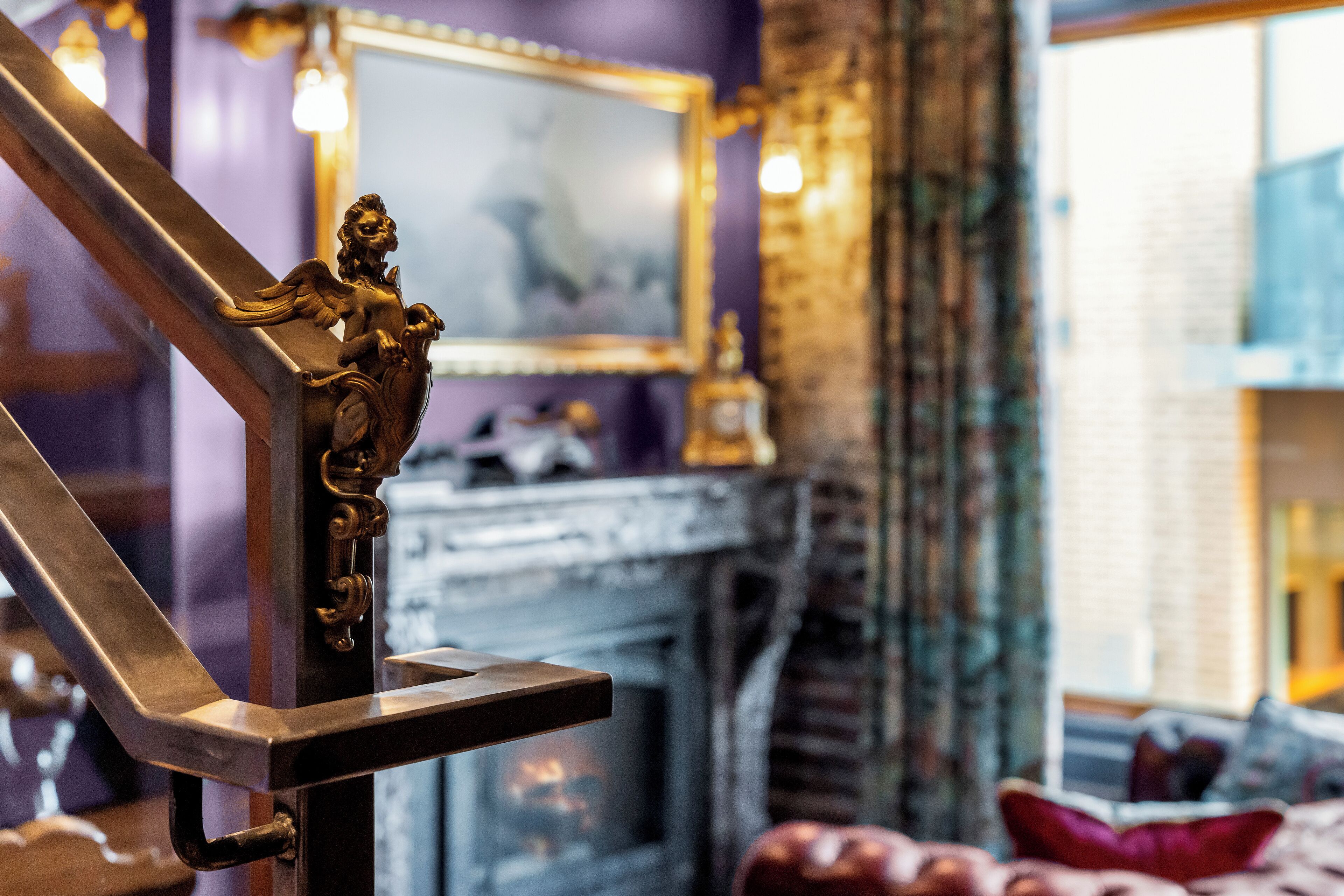 A staircase with a decorative angel figure, a fireplace, and a mirror on the wall.