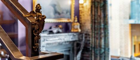 A staircase with a decorative angel figure, a fireplace, and a mirror on the wall.