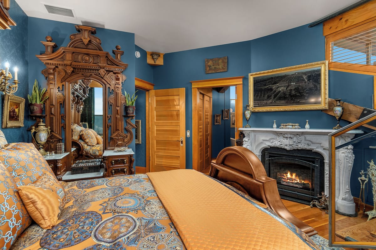 Een slaapkamer met een groot bed, een open haard en een houten kast.