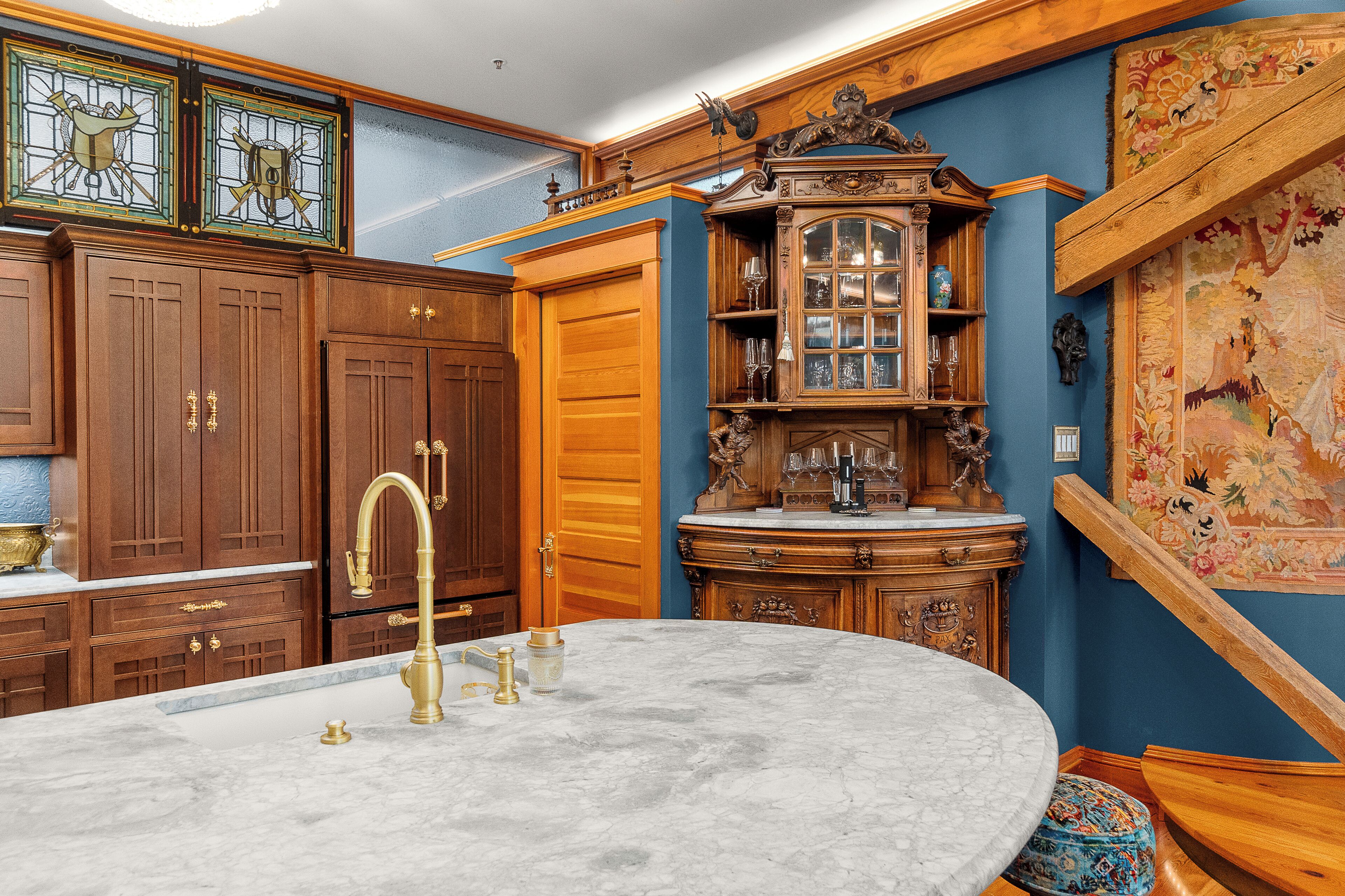 A kitchen with wooden cabinets, a marble countertop, and a decorative clock.