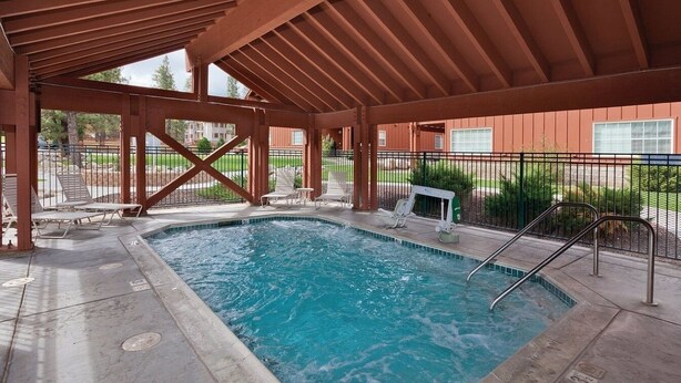 Une piscine couverte dotée d’une terrasse en bois, de chaises longues et d’un petit espace salon.