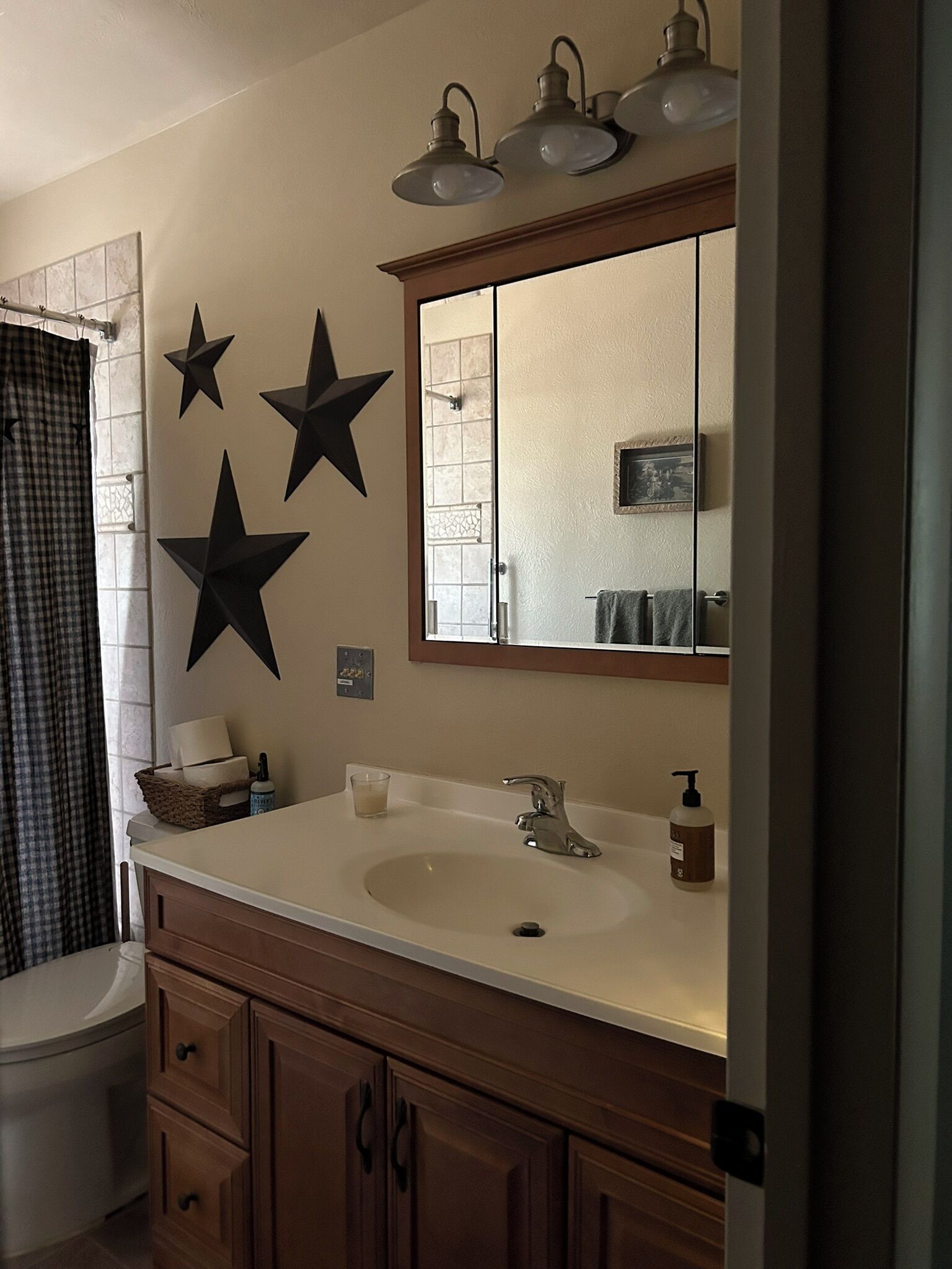A bathroom with a sink, mirror, and three black star decorations on the wall.