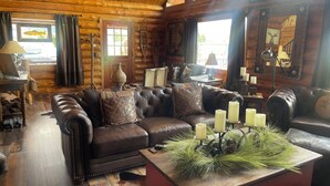 A cozy log cabin interior with a leather sofa, a vase, and candles.