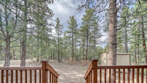 A wooden deck with a view of a forested area and a small shed.
