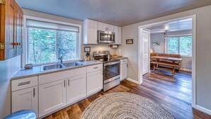 A modern kitchen with white cabinets, a built-in microwave, and a large window.