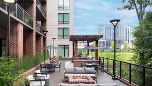 Eine Dachterrasse mit Sitzgelegenheiten im Freien, einem Grillbereich und einer Pergola.