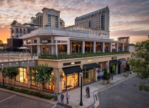 A hotel with a modern architectural design, featuring a rooftop terrace and a ground-level shopping area.