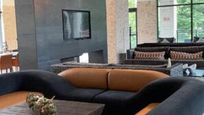 Ein modernes Wohnzimmer mit einem Ecksofa, einem Couchtisch und einem großen Fenster mit Blick auf Grünflächen.