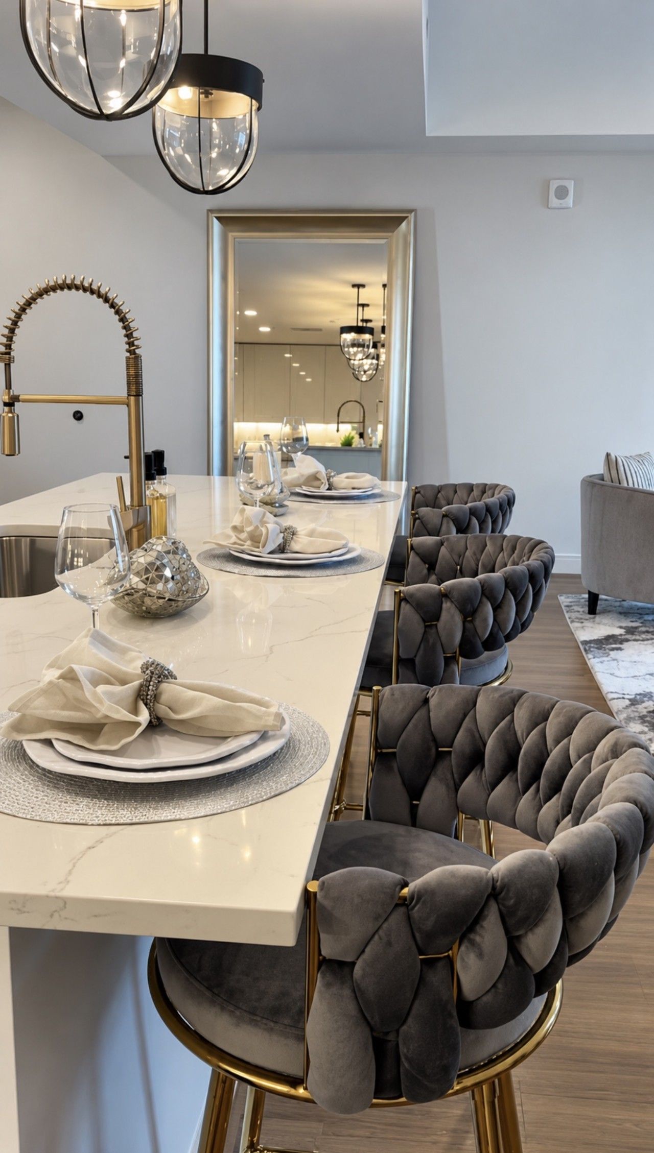 A modern dining area with a long table, cushioned chairs, and pendant lighting.