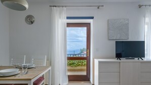 A modern kitchen with a wooden table, white cabinets, and a television. - Apartment Yasmin (Kvarner - Mošćenička Draga) (Mošćenička Draga)