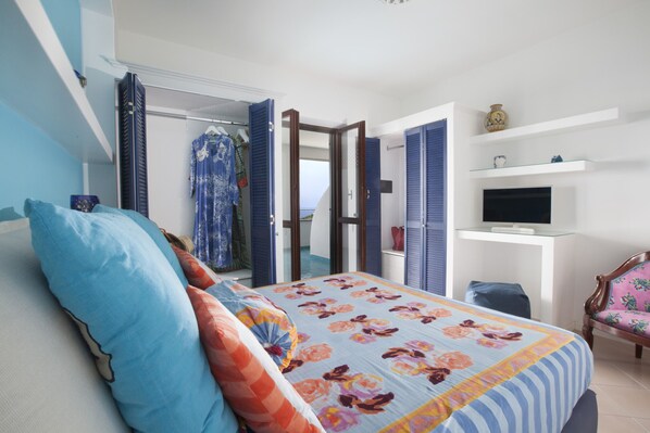 A bedroom with a bed, a wardrobe, a television, and a chair.
