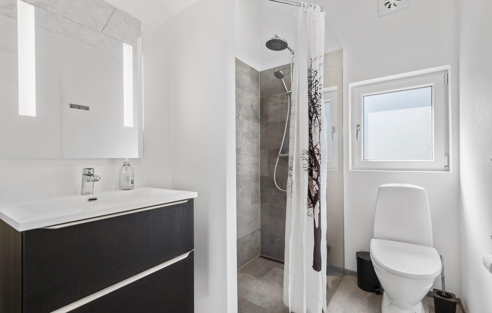 A modern bathroom with a shower, toilet, and vanity.