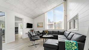 Una sala de estar moderna con un sofá modular, una mesa de centro y un televisor montado en la pared.