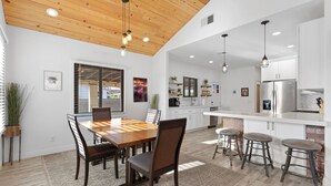 A modern kitchen with wooden ceiling, white cabinets, and a central island with stools. - Charming House in Downtown Phoenix (Phoenix)